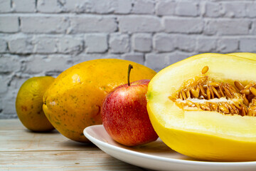 Table of fruits. Melon, papaya, orange, and slices of apple on a wooden table. Selective focus.