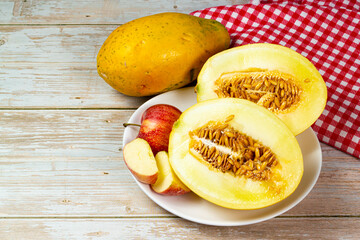 Table of fruits. Melon, papaya, and slices of apple on a wooden table. Selective focus, top view.