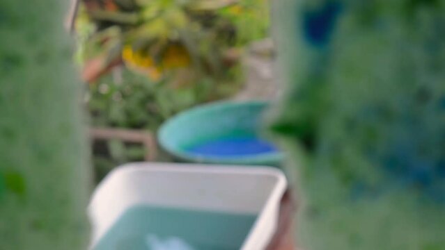 Sheet of recycled paper drying on a glass window and two plastic basin full of paper pulp in the background. Homemade paper process.