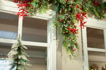 Decorated window of the house for winter holiday season. Classic red Christmas home decor with a decorative garland and xmas tree. 