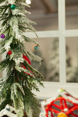 Decorated window of the house for winter holiday season. Classic red Christmas home decor with a decorative garland and xmas tree vertical shot. 