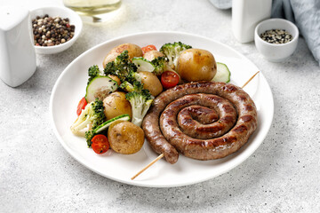 Grilled pork sausages and potatoes, broccoli on white plate. Dinner dish, lunch BBQ. Homemade Snail round sausage.