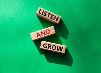 Listen and grow symbol. Concept words Listen and grow on wooden blocks. Beautiful green background. Businessman hand. Business and Listen and grow concept. Copy space.
