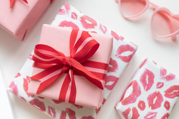 Gift boxes with red bow with heart shaped sunglasses on the white background. Valentine's day concept close up
