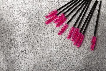Eyelash extension brushes on a black marble background. Brush for combing extended and false eyelashes. Brush for straightening eyelashes and eyebrows.