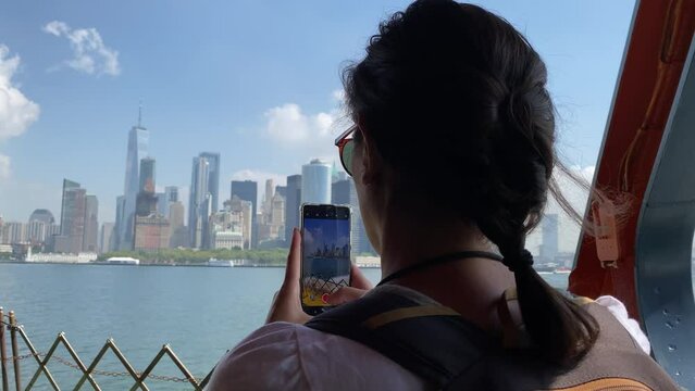 Young woman taking picture with smartphone staten island ferry magnificent views of skyscrapers in manhattan new york buildings seen from the river concept lifestyle city vacation adventu