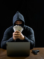 Hacker spy man hands wearing a black shirt, sitting on a chair and a table, is a thief, holding...