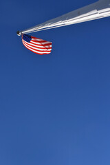 Oblique view up flag pole to old glory blowing in the wind. Focal point in top edge of frame.  