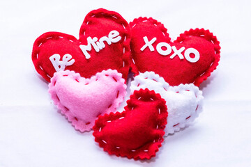 Five cloth hearts, two larger ones with text and three plain smaller ones on a white background