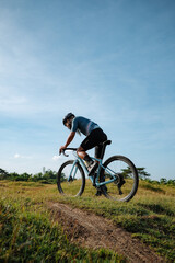 Fototapeta premium A young bearded cyclist is biking through a field