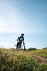 Fototapeta na wymiar A young bearded cyclist is biking through a field