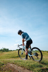 Obraz premium A young bearded cyclist is biking through a field
