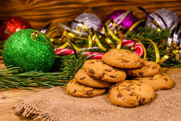 Obraz na płótnie Canvas Pile of the chocolate chip cookies on sackcloth in front of christmas decorations