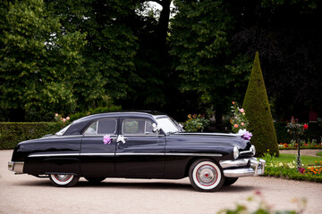 A vintage black car is decorated and waiting ready to take the bride and groom after the ceremony