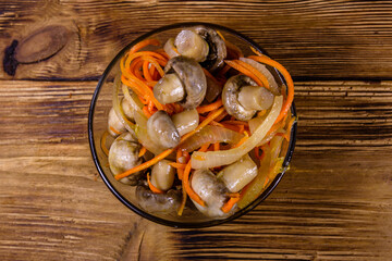 Canned mushrooms with carrot and onion in a ceramic bowl. Top view