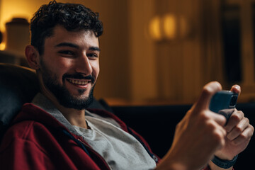 Close up view of a young man holding a phone and looking at the camera