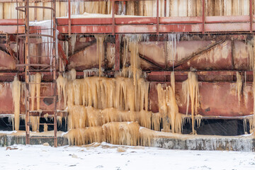frozen icicles of rusty water on pipes and wires