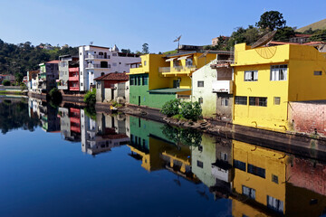Fototapeta na wymiar Colorful houses in Pirapora do Bom Jesus reflect in the calm waters of the Tiete River. Sao Paulo State, Brazil