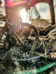 Conceptual image of a burnt-out bus with a sun in the background and twisted ash and iron with blurred city in the background