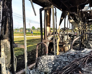 Burned bus with open doors seen from the inside with a person running in the background