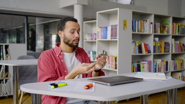 Multitasking African American student turns off laptop when finished working dissertation in library