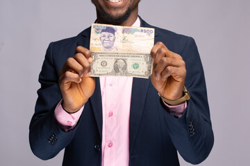 african man holding naira and dollar bills