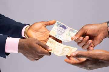 two black people exchanging naira and cedi