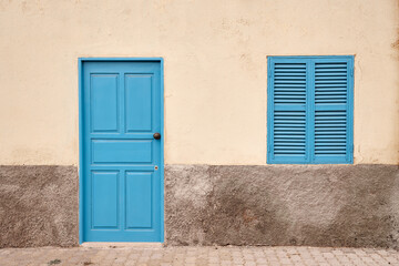 Fototapeta premium A white wall with a blue door and window.