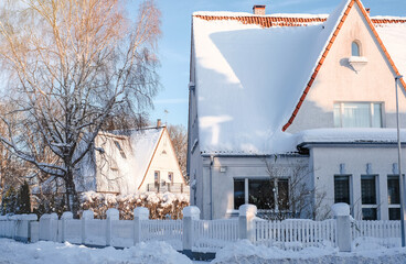 Winter fairy-tale landscape on the street with houses with a triangular roof and roads covered with...