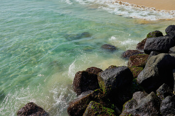 Rocks and waves on a sandy tropical beach.