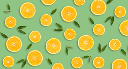 Pieces of fresh oranges with green leaves on green background. Pattern for design