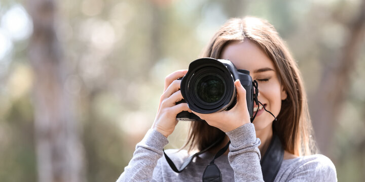 Beautiful female photographer with modern camera outdoors