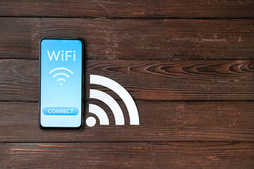 Mobile phone with WiFi symbol and connection button on wooden background