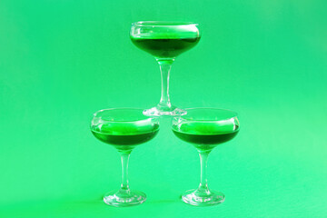 Glasses of tasty cocktail on green background
