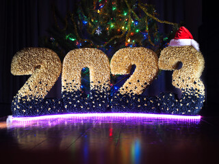 new year 2023. numbers of the year in yellow color on the background of multi-colored bokeh. New Year's date. New Year's installation against the background of lanterns. numbers on a bokeh background.