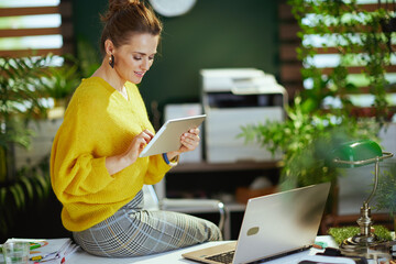 business owner woman in sweater in green office using tablet PC
