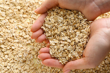 Female hands full of raw oatmeal, closeup