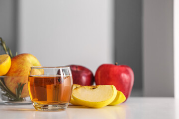 Glass of tasty apple juice and fresh fruits on table