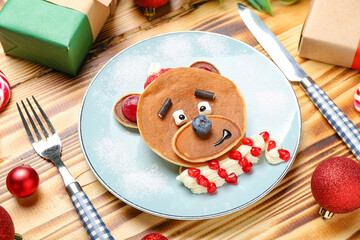Fototapeta na wymiar Plate with bear made of pancakes, fruits and Christmas decor on wooden table, closeup