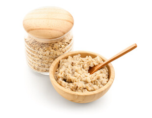 Wooden bowl of tasty oatmeal and jar with flakes isolated on white background