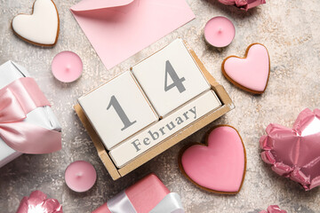 Cube calendar with date 14 FEBRUARY, cookies, envelope, candles and gifts on grunge background