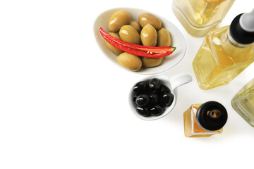 Bottles of different cooking oils and olives on white background, above view