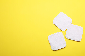 Soft clean cotton pads on yellow background, flat lay. Space for text