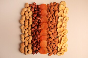 Mix of delicious dried nuts and fruits on beige background, flat lay