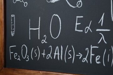 Different mathematical formulas written with chalk on blackboard, closeup