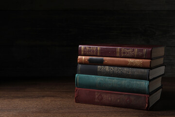 Stack of old hardcover books on wooden table, space for text