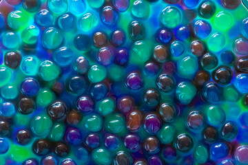 Fototapeta na wymiar orbiz balls in water.Hydrogel balls for decoration, gardening and air humidifier.Beautiful background in cool blue and green colors.Hydrogel Orbeez background.multicolored orbiz texture.