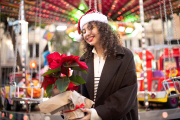 Macro, model in a santa hat with a poinsettia flower on a bright background. christmas holiday