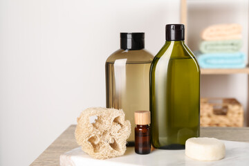 Solid shampoo bar and bottles of cosmetic product on wooden table in bathroom, space for text