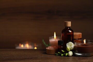 Beautiful spa composition with burning candles, different care products and flowers on wooden...